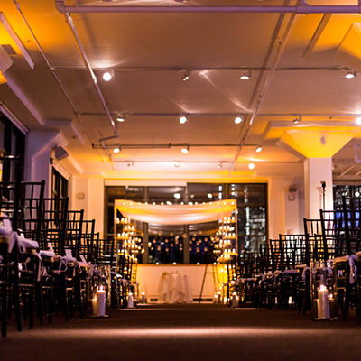 photo: elegant indoor ceremony setup with orange uplighting